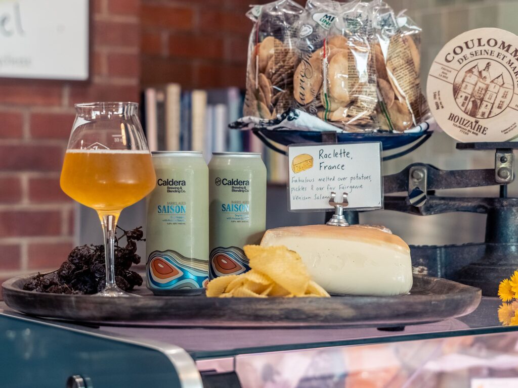 Raclette cheese board with craft beer and snacks on a cozy table