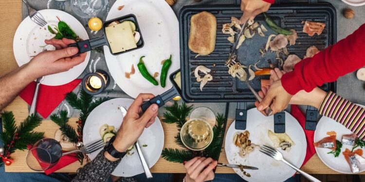 Tradiciones de raclette fundida de todo el mundo en tabla rústica