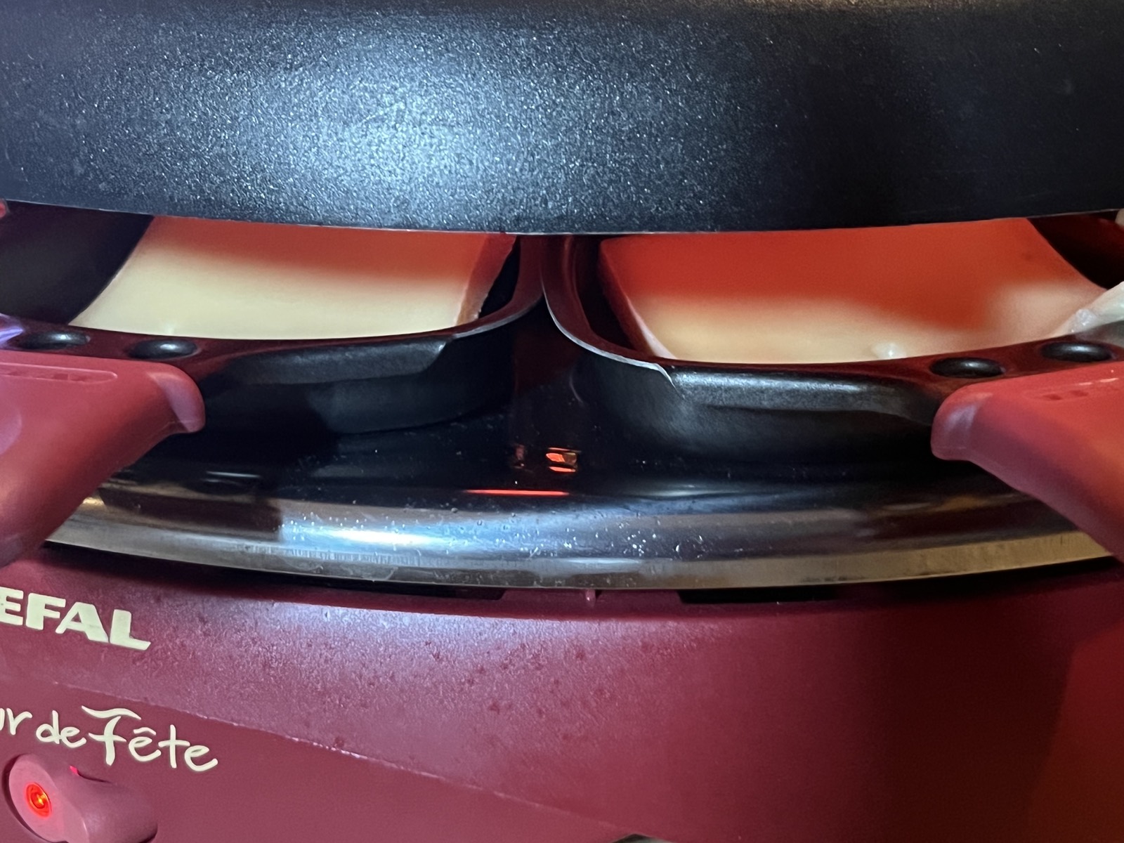 Raclette coupelles inside electric raclette machine — cleaning cheese trays after use