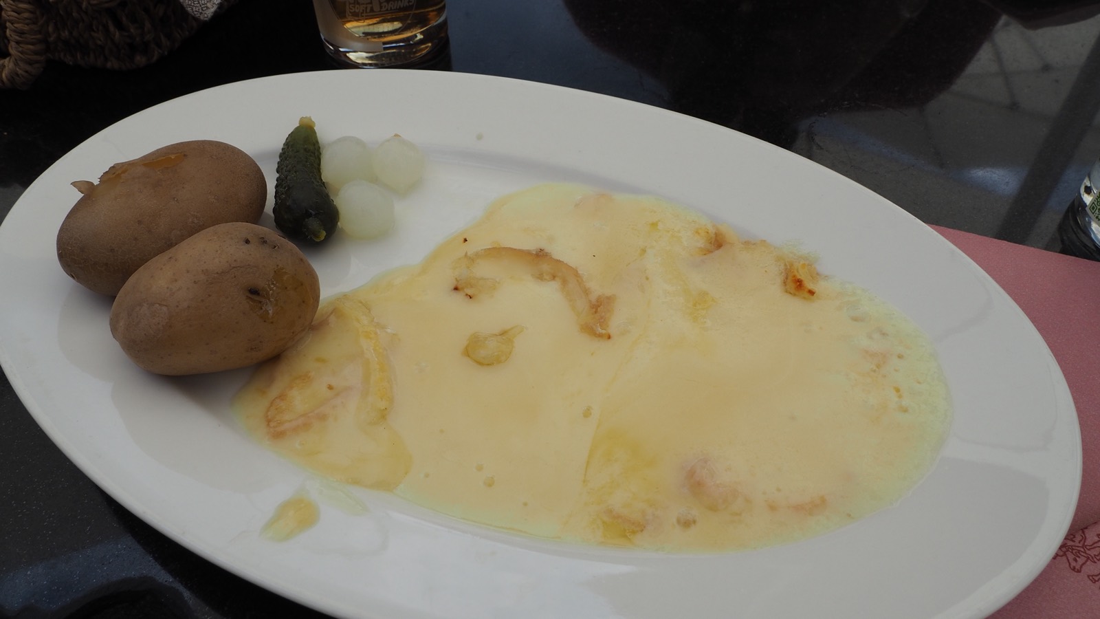 Elektro-Raclette-Grill mit individuellen Pfännchen rund um einen geselligen Tisch — traditionelles Schweizer Raclette-Rezept