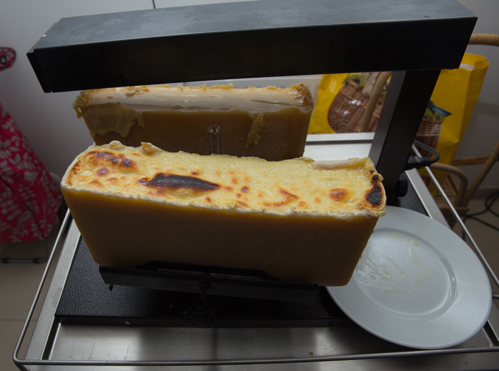 large raclette dinner table with cheese, potatoes and charcuterie for a crowd
