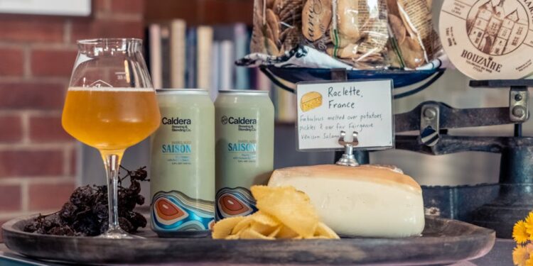 Set de raclette portátil con queso fundido al aire libre sobre mesa de madera
