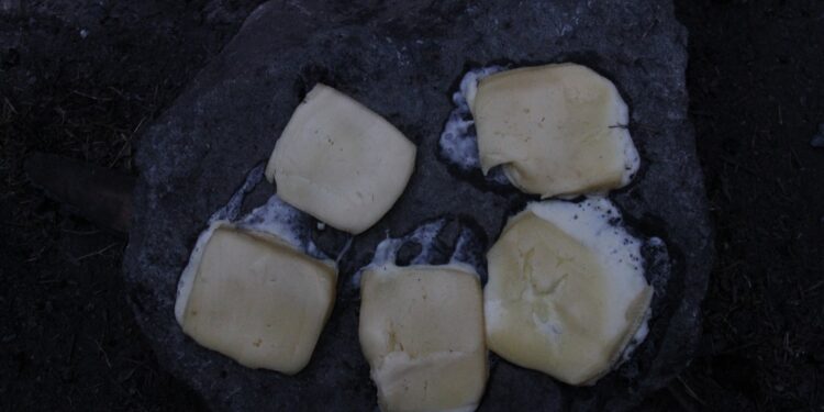 melting raclette cheese scraped from open flame — raclette without a machine